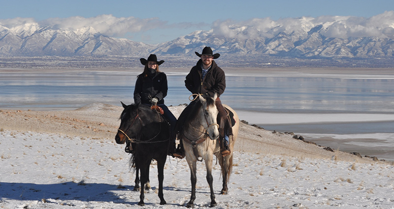 Logistics coach riding on horseback in front of mountains and lake